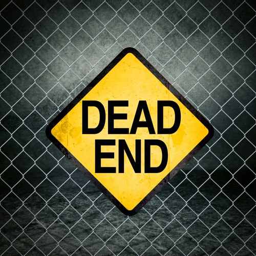 Dead End Grunge Yellow Warning Sign on Chainlink Fence of Industrial Warehouse